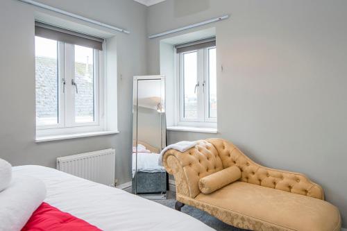 ein Schlafzimmer mit einem Bett, einem Stuhl und einem Spiegel in der Unterkunft Inkerman House in Saundersfoot