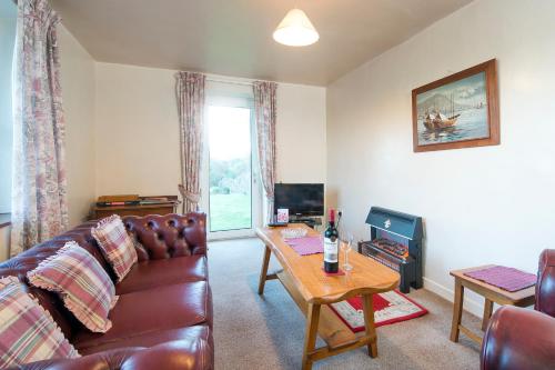 a living room with a couch and a table at Lower Coach House in Fishguard