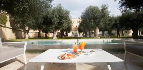 a table with a plate of food on it next to a pool at La Fiermontina Luxury Home Hotel in Lecce