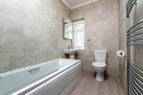 a bathroom with a tub and a toilet and a sink at The Rath in Saundersfoot