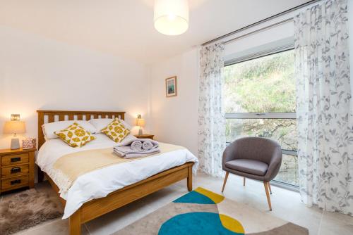 a bedroom with a bed and a chair and a window at 16 Waters Edge in Tenby
