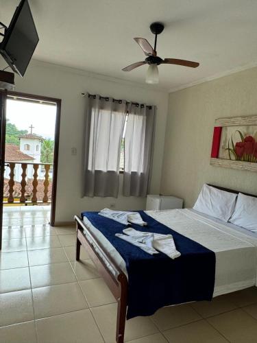 a bedroom with a bed with a ceiling fan at Pousada Marcondes in Paraty