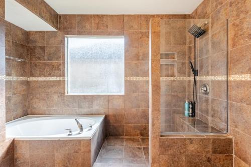 a bathroom with a tub and a glass shower at Stunning 4-Bedroom Spacious 2-Story Home in Buda