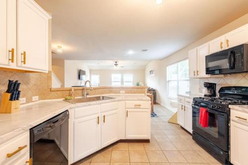 a kitchen with white cabinets and a sink and a stove at Stunning 4-Bedroom Spacious 2-Story Home in Buda