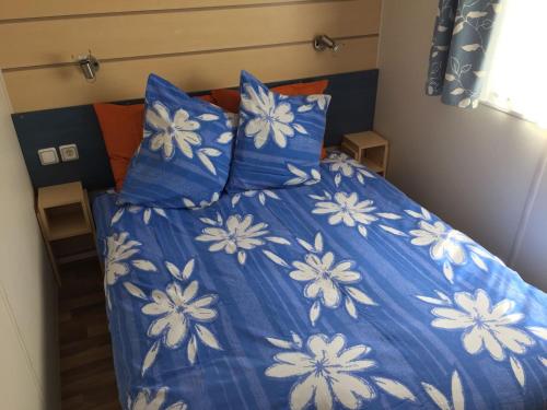 a bed with blue and white sheets and pillows at Mobilhome Ferme équestre La Mouillère in Chalabre