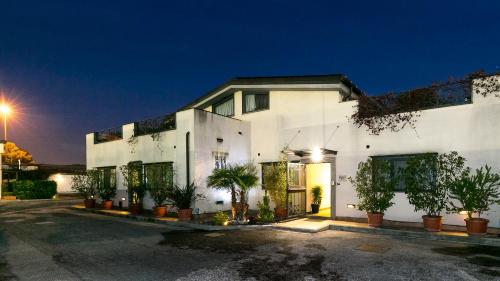 a white building with potted plants in a parking lot at Hotel Residenza Gra 21 in Rome
