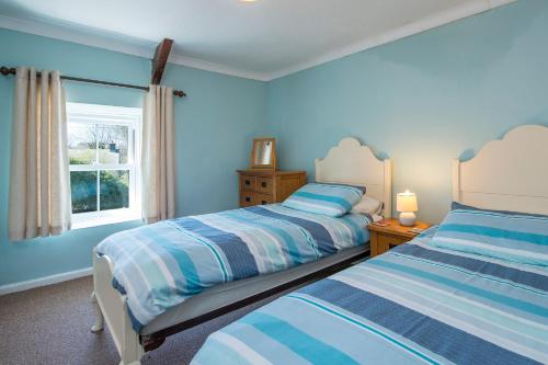 a blue bedroom with two beds and a window at 3 Tower Hill in Dinas