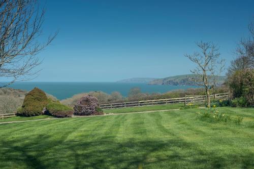 a field of grass with a fence and a lake at 3 Tower Hill in Dinas