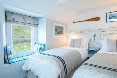 deux lits dans une chambre blanche avec une fenêtre dans l'établissement Tri Pysgodyn, à Haverfordwest