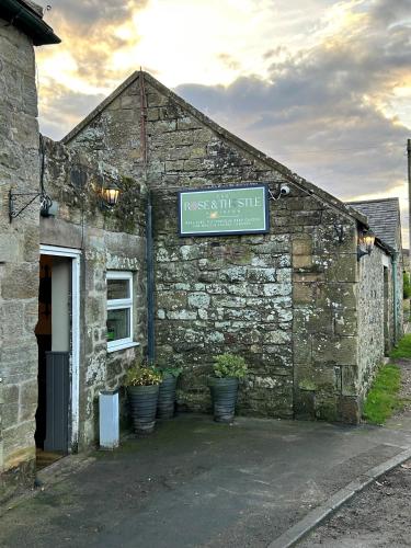 an old stone building with a sign on it at The Rose and Thistle Alwinton in Morpeth