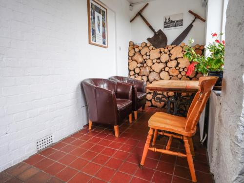 a room with chairs and a table and a pile of logs at YHA Eskdale in Eskdale
