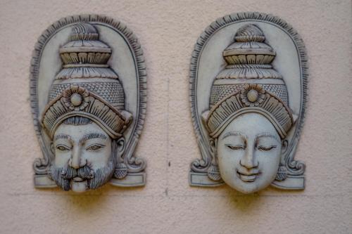 two statues of faces are on a wall at Monkey villa in Hikkaduwa