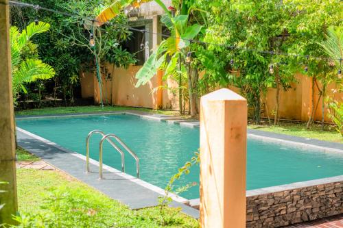 a swimming pool in a yard next to a house at Monkey villa in Hikkaduwa