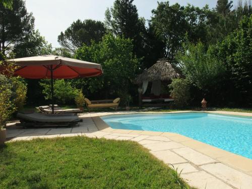 a swimming pool with an umbrella and a table and chairs at Gite La Paillote in Montauroux