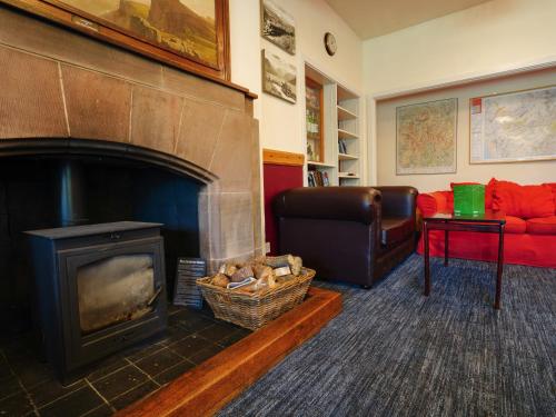 a living room with a fireplace and a red couch at YHA Eskdale in Eskdale