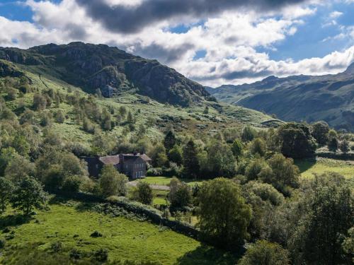 a house in a valley with mountains in the background at YHA Eskdale in Eskdale