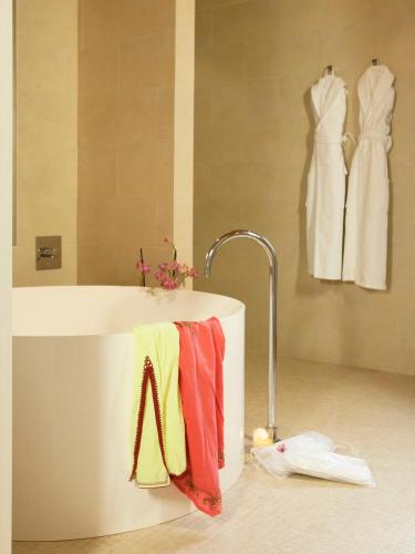 a bathroom with a tub with a towel and two dresses at La Fiermontina Luxury Home Hotel in Lecce