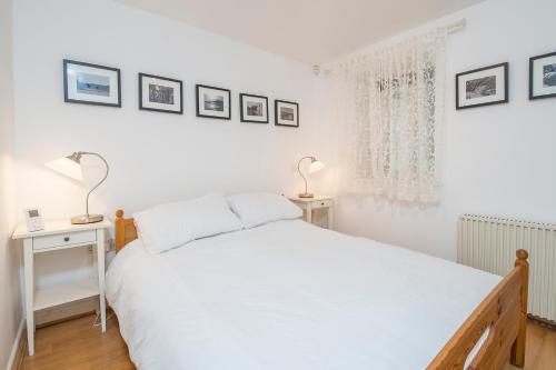 a white bedroom with a bed and two lamps at Picture Cottage in Solva
