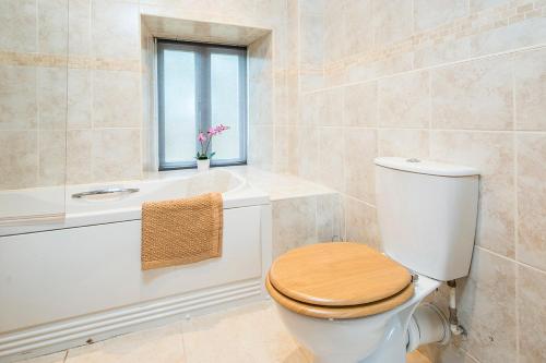 a bathroom with a toilet and a tub and a window at Picture Cottage in Solva