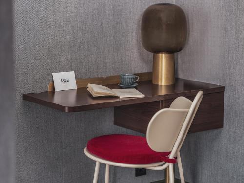 a desk with a red chair and a table with a lamp at Bob Hotel in Paris