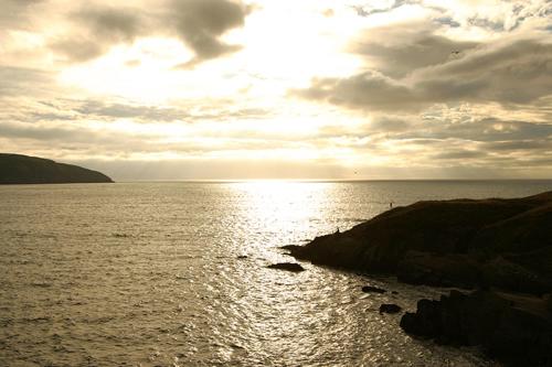 a sunset over a body of water with the sun shining at Nantsaeson in Cardigan
