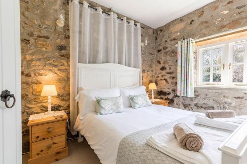 ein Schlafzimmer mit einem weißen Bett und einer Steinwand in der Unterkunft Little Rogeston Cottage in Haverfordwest