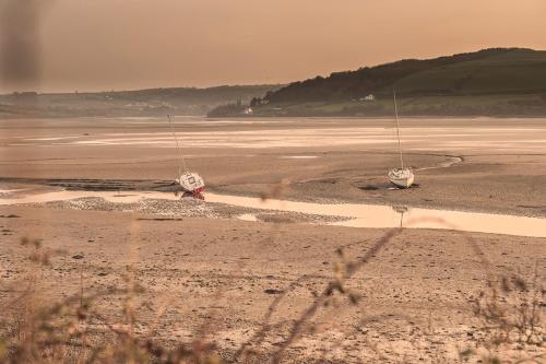 two boats are sitting on the shore of a beach at Nantsaeson in Cardigan