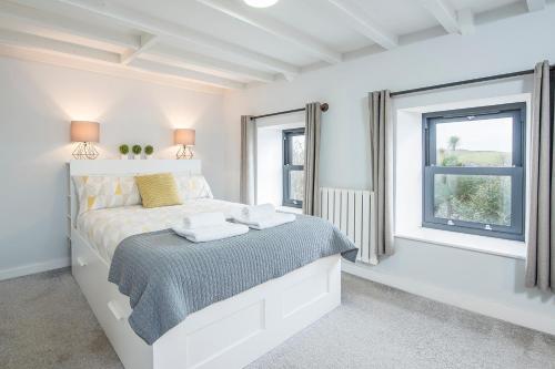 a white bedroom with a bed and a window at Ty Cranc Mawr in Haverfordwest