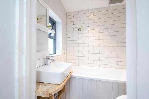a white bathroom with a sink and a tub at Ty Cranc Mawr in Haverfordwest