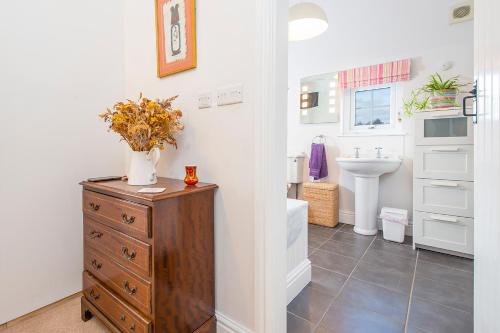 ein Badezimmer mit einer hölzernen Kommode mit einer Blumenvase darauf in der Unterkunft Llanmill Cottage in Lampeter-Velfrey