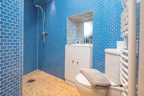 a blue tiled bathroom with a toilet and a sink at Lower Deck in Tenby