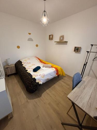 une chambre avec un lit, une table et une chaise dans l'établissement Appartement T4 Quartier Moulin à vent, à Perpignan