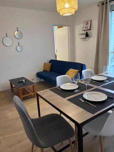 une table à manger avec des chaises et un canapé bleu dans l'établissement Appartement T4 Quartier Moulin à vent, à Perpignan