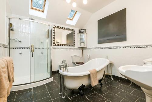 a bathroom with a tub and a shower and a sink at Waterwynch House in Tenby