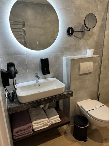 a bathroom with a sink and a toilet and a mirror at Guest House Zatyshnyi Dvir in Bukovel