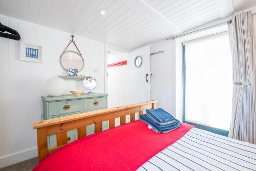 Un dormitorio con una cama con una manta roja y una ventana. en The Boathouse, en Cardigan
