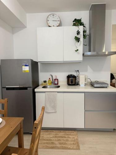 una cucina con mobili bianchi e un orologio sul muro di Dwell a Manila
