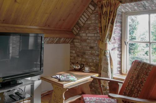 a living room with a tv and a table with a table at Natuurpoort van Loon in Loon op Zand