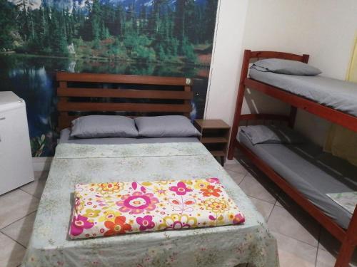 a bedroom with two bunk beds and a painting at Pousada Aconchego in Peruíbe
