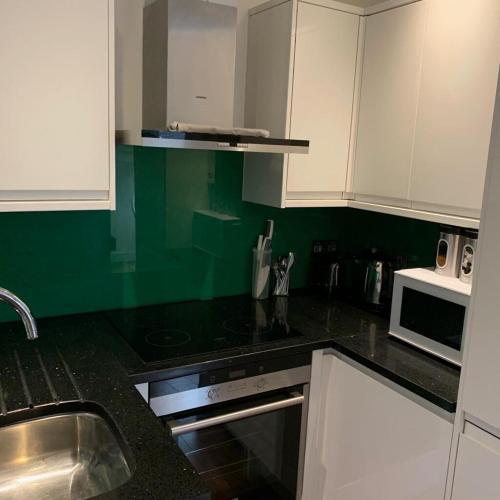 a kitchen with white cabinets and a black counter top at City Center Camden Market Budget Apartment and Rooms in London