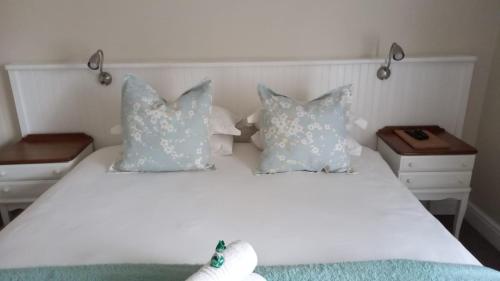 a bedroom with a white bed with pillows at 137 High Street Guest House in Grahamstown