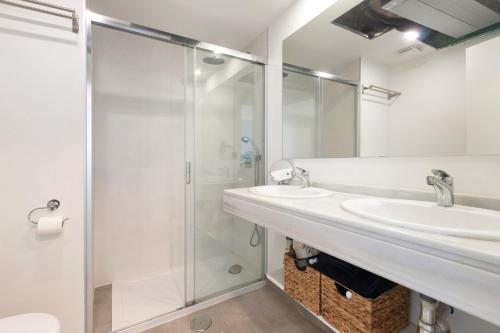 Un baño blanco con dos lavabos y una ducha. en Seaview apartment Alba, en Torrequebrada