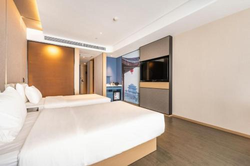 a bedroom with two beds and a flat screen tv at Atour Hotel (Xi'an Xiaozhainan, Qujiang Convention and Exhibition Center) in Xi'an