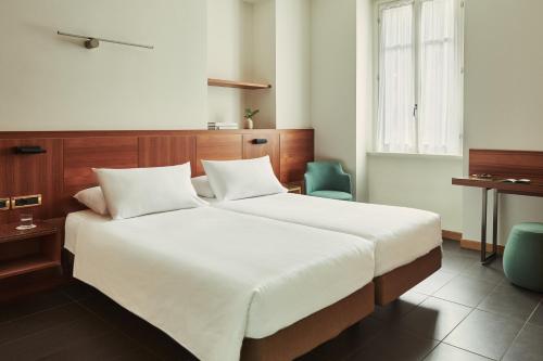 a bedroom with a large white bed and two chairs at Hotel Belvedere in Bellagio