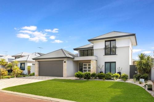 a large white house with a green lawn at 2 Story luxury beach house in Geographe