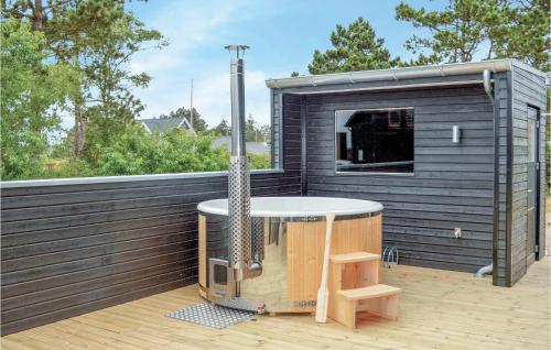 a small black shed with a hot tub on a deck at Three-Bedroom Holiday Home In Romo in Sønderby