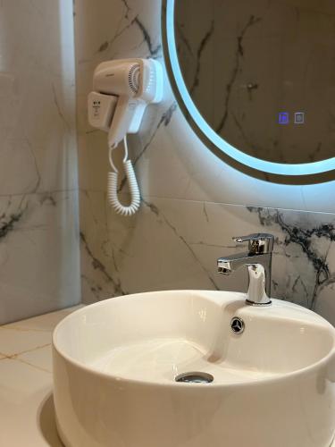 a white sink in a bathroom with a phone at The Roots Boutique Hotel in Shkodër