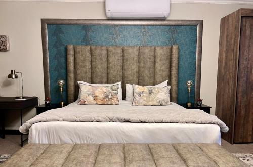 a bedroom with a large bed with a blue headboard at One O Eight Boutique Hotel in Benoni