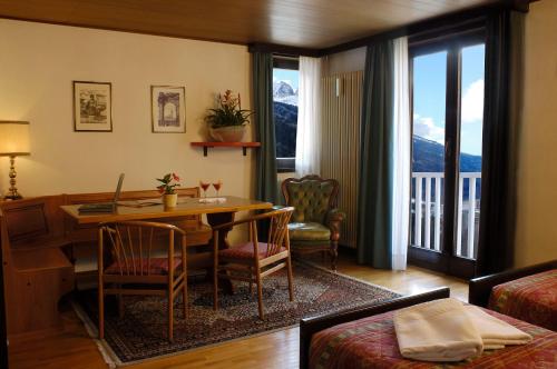 un soggiorno con scrivania e tavolo con sedie di Hotel Mirella a Ponte di Legno