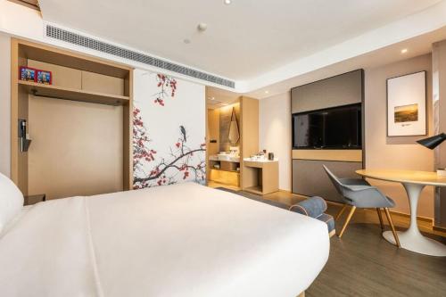 a hotel room with a large white bed and a table at Atour Hotel (Xi'an Xiaozhainan, Qujiang Convention and Exhibition Center) in Xi'an